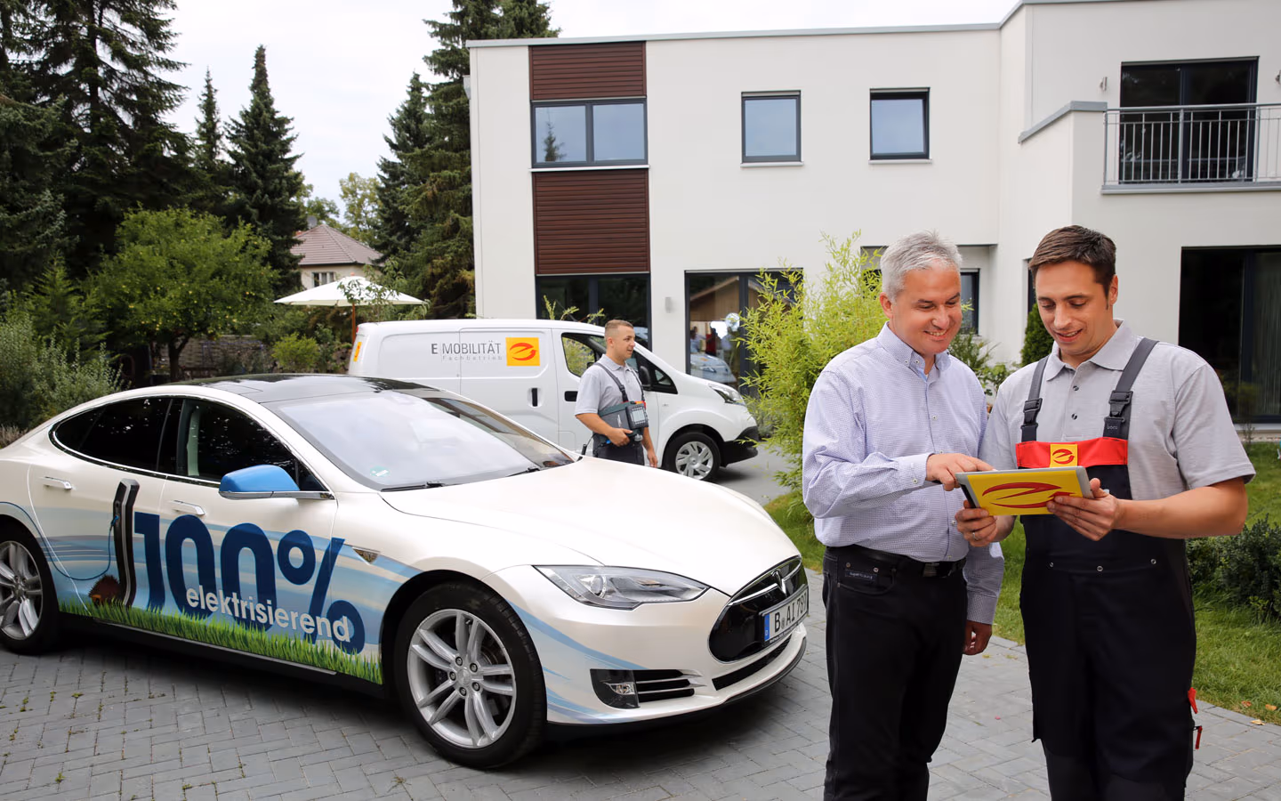 E-Mobilität - Mitarbeiter mit Kunden vor Elektrofahrzeugen 100% elektrisch &middot; Thoma-Laudan Gebäudetechnik