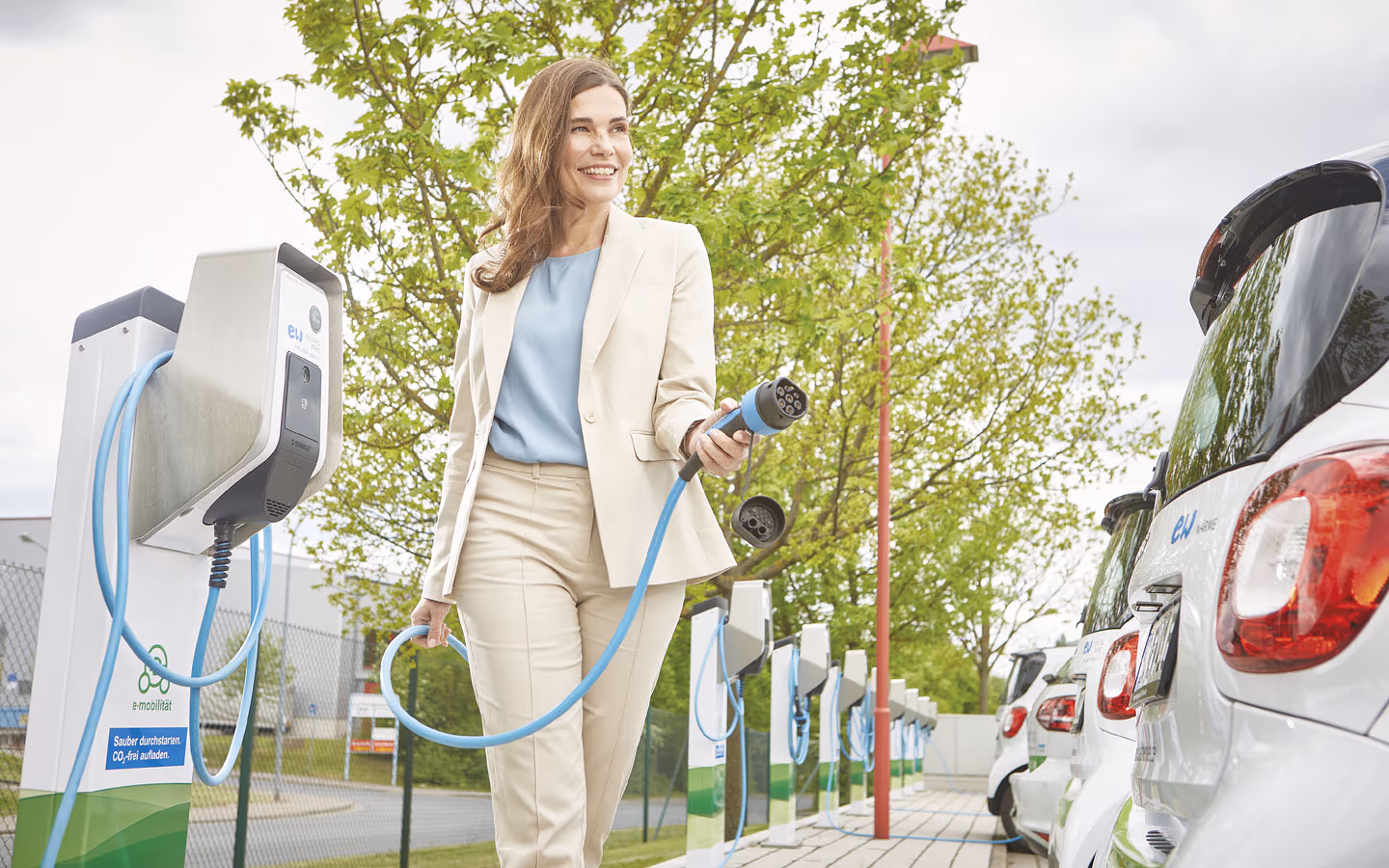 E-Mobilität - Kundin vor Ladestation mit Stecker in der Hand &middot; Thoma-Laudan Gebäudetechnik