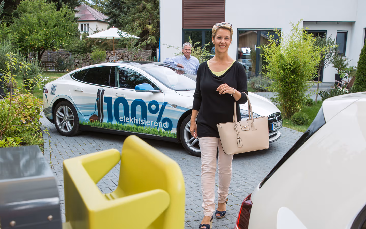 E-Mobilität - Kundin vor Elektrofahrzeugen 100% elektrisierend &middot; Thoma-Laudan Gebäudetechnik